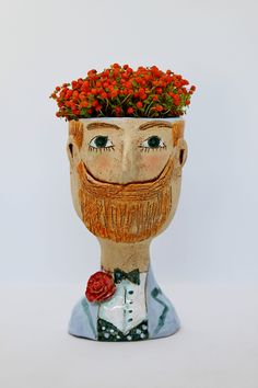 a ceramic head with a beard and flowers in it's hair is shown against a white background