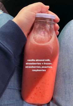 a person holding a glass bottle filled with fruit and vegtables on their lap