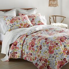 a bed with floral comforter and pillows in a room