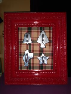 three pieces of metal in a red frame on a purple tablecloth with a black and white checkerboard background