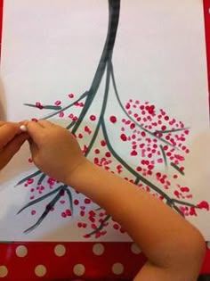 a child is painting a christmas tree with red and white polka dots on the paper