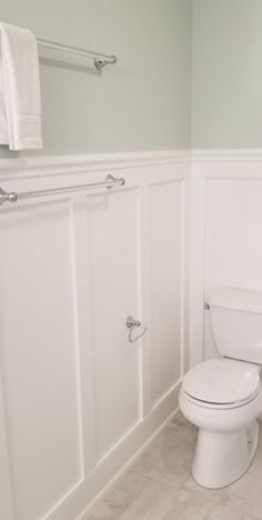 a white toilet sitting in a bathroom next to a sink and towel rack on the wall