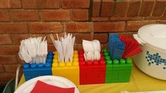 several legos are lined up on a table next to a bucket and paper plates