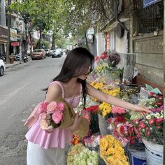 a woman standing in front of a flower stand with flowers on it's sides