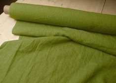 an unmade bed with green sheets on it and a roll of paper next to it