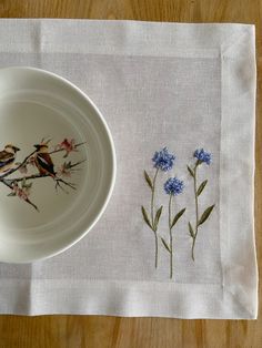 a white plate sitting on top of a wooden table next to a blue and white flower