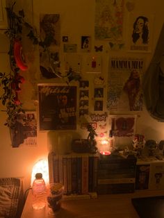 a living room with posters and candles on the wall next to a table filled with books