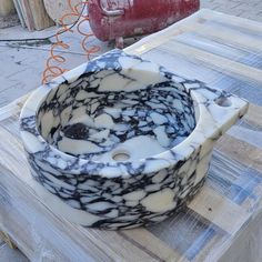 a marble sink sitting on top of a wooden table next to a red fire hydrant