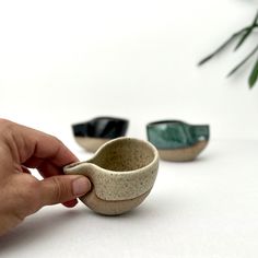 a hand holding a small cup in front of three smaller bowls