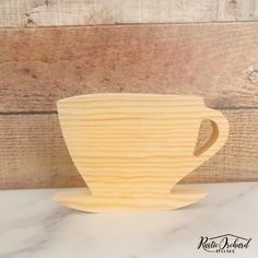 a wooden coffee cup sitting on top of a white marble counter next to a wood plank wall