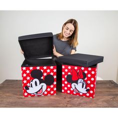 a woman standing next to two boxes with minnie mouse designs on them