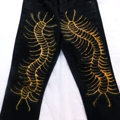 a pair of black jeans with yellow embroidered designs