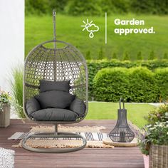 a chair and table on a wooden deck with plants in the backgroung