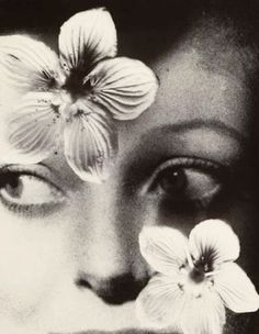 a black and white photo of a woman with flowers on her face