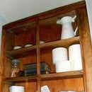 a wooden shelf filled with lots of white dishes