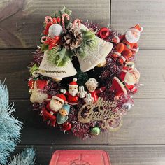 a christmas wreath with ornaments and decorations on it next to a red tinsel box