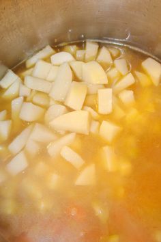 a pot filled with soup and diced potatoes on top of the stove burner