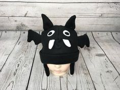 "Baby and Kids Black Bat Fleece Hat This is a bat hat made from black fleece. It features felt eyes, fleece teeth, fleece ears, and fleece wings. Hat Sizes: Baby: Approx. 20\" around Child: Approx. 22\" around Youth: Approx. 23 1/2\" around Hat shown is a child size on a 18 1/2\" (47cm) head. Care: Machine wash on cool or warm; dry on low. Turnaround time is 1-3 business days. Standard Shipping is usps first class (3-5 business days). Upgrade to priority (2-3 day) and priority express (1-2 day) Black Felt Hat For Halloween Costume, Black Novelty Beanie Hat, Novelty Black Beanie Hat, Themed Black Costume Hats For Winter, Black Novelty Hat For Halloween, Whimsical Black Adjustable Hat, Black Beanie For Halloween, Black Whimsical Costume Hats, Themed Black Winter Hats