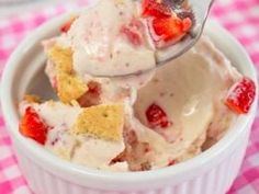 a bowl filled with ice cream and strawberries on top of a checkered table cloth