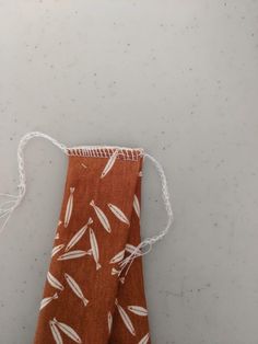 a piece of cloth with white thread hanging from it's end on a table