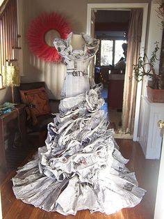 a dress made out of newspapers sitting on top of a wooden floor next to a doorway