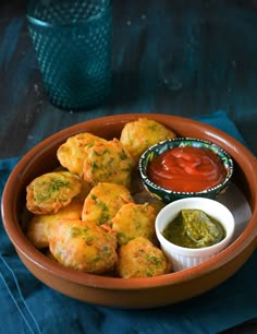 a bowl filled with fried food next to a dipping sauce on a blue table cloth