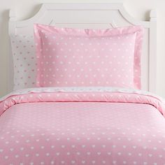 a bed with pink and white hearts on the comforter, pillows and pillow cases