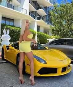 a woman standing next to a yellow sports car in front of a building with bunny ears on her head