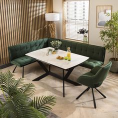 a corner table with two green chairs and a white marble top