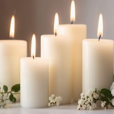 white candles are lined up next to flowers