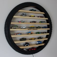 there are many toy cars on the shelf in the circle shaped display case that says alex's garage