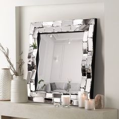 a mirror sitting on top of a mantle next to candles