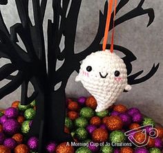 a crocheted stuffed animal hanging from a tree with balls in front of it