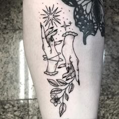 a black and white tattoo on the leg of a woman's leg, with an image of two hands reaching for a butterfly