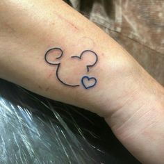 a person with a mickey mouse tattoo on their left arm and the outline of a heart in the shape of a mouse