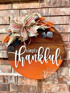 a wooden sign that says simply thank with leaves and pumpkins on the side of a brick wall