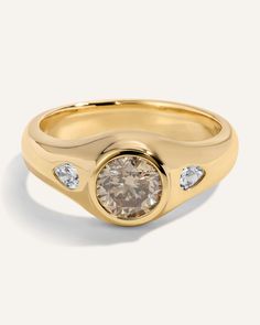 a yellow gold ring with two diamonds on the side and a center stone in the middle