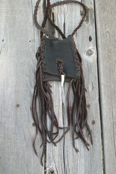 a brown leather purse with fringes hanging from it's side on a wooden fence