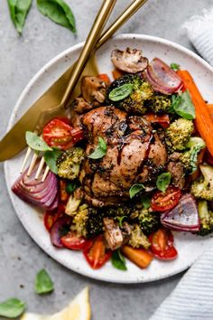 a white plate topped with meat and veggies on top of a gray table