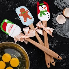 four wooden spoons decorated with snowmen and ginger cookies on top of a table