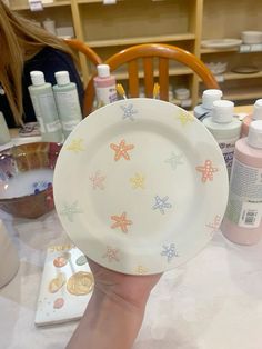 a person holds up a plate with starfish designs on it, while other items sit in the background