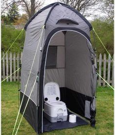 an outdoor toilet in the grass with its door open