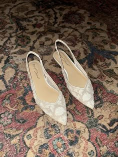 two pairs of white shoes sitting on top of a rug