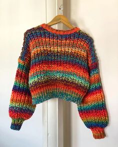 a multicolored sweater hanging on a white door with a wooden hanger in front of it