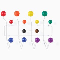 an assortment of colorful balls and pegs on a white wall mounted rack with hooks