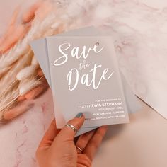 someone holding up a wedding card with the word save the date written on it in white