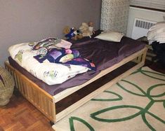 an unmade bed sitting on top of a hard wood floor next to a radiator