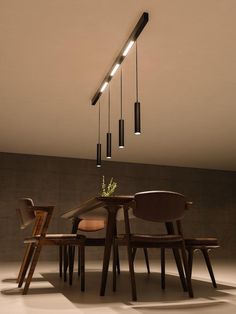 a dining table with chairs and lights hanging from the ceiling