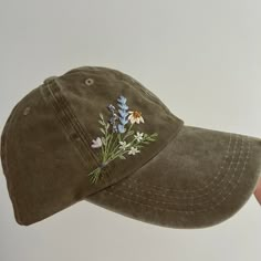 a person wearing a hat with flowers on the front and side, while holding it in their hand