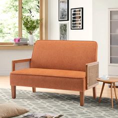 an orange couch sitting on top of a rug in a living room